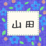 青い花柄の布地に名札が縫ってあるようなデザインの画像「山田」と手書き風で書いてある